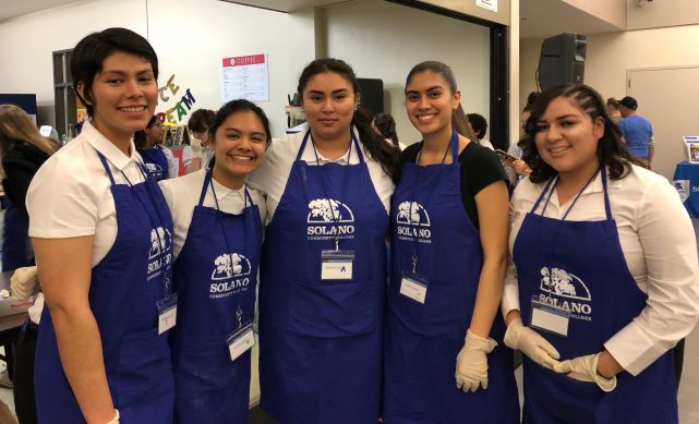 Students with aprons working at the crab feed