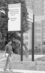 student next to campus signage