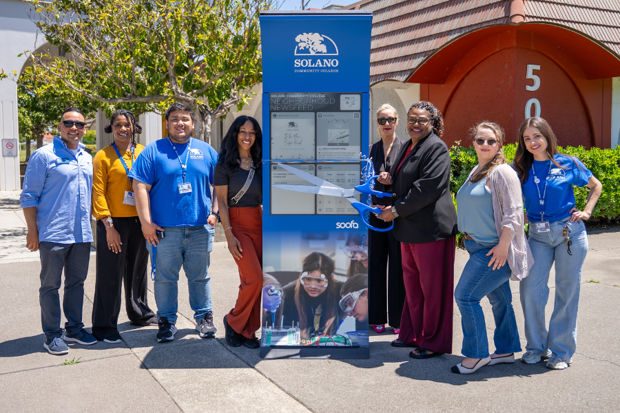 People stand next to ribbon cutting of sign